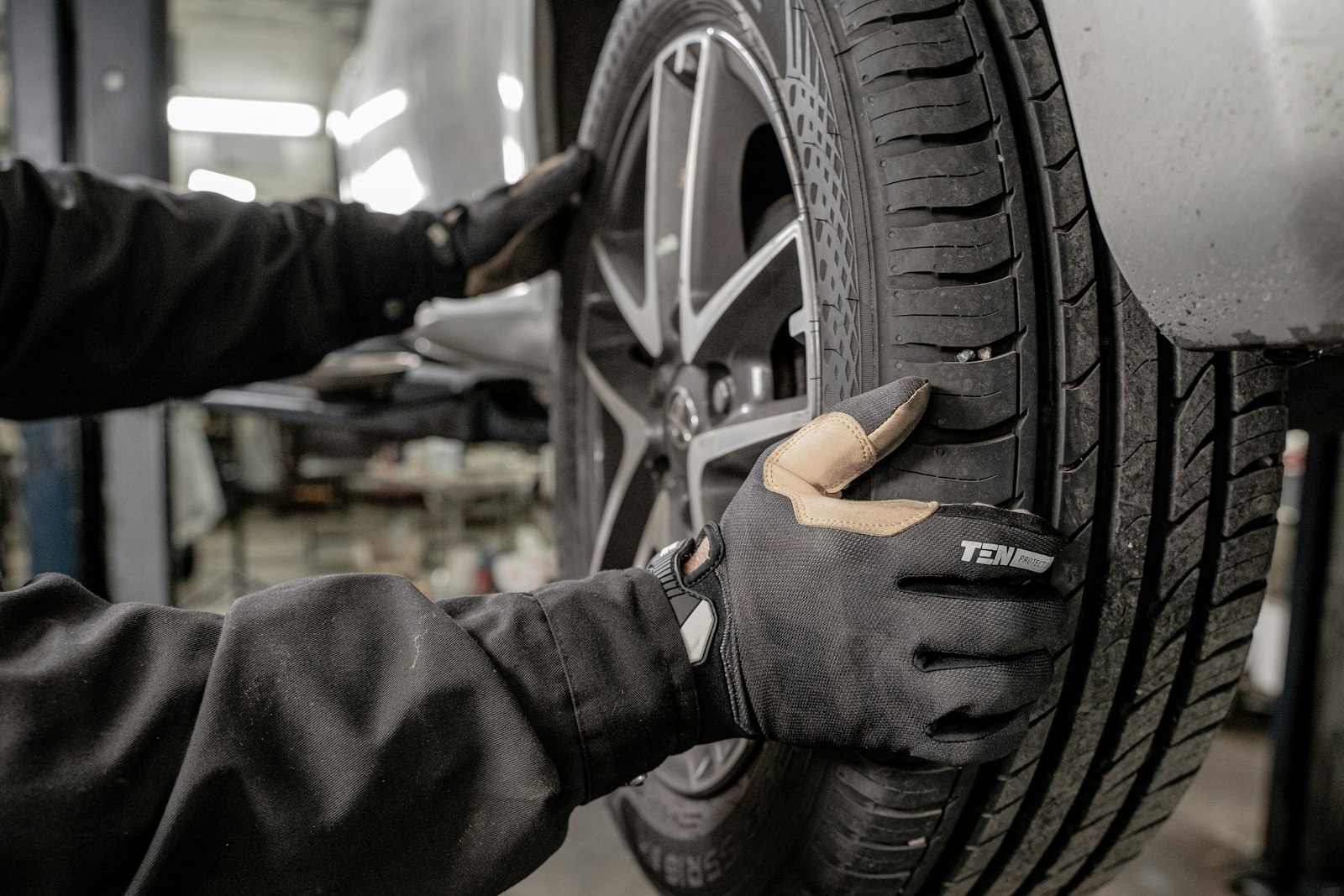Técnico con guantes revisando la llanta de un auto en el taller